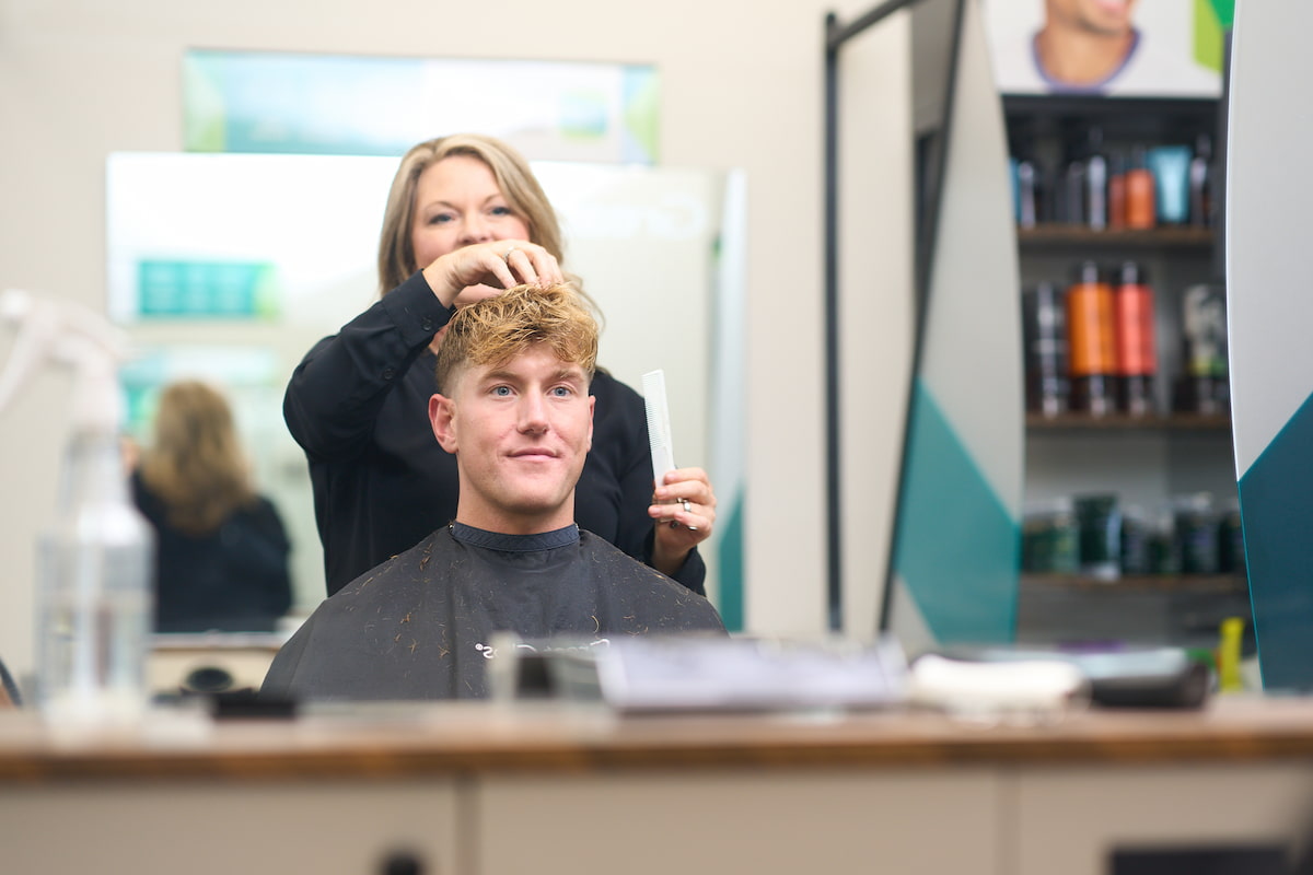 Blonde haired male getting his hair styled in a salon chair