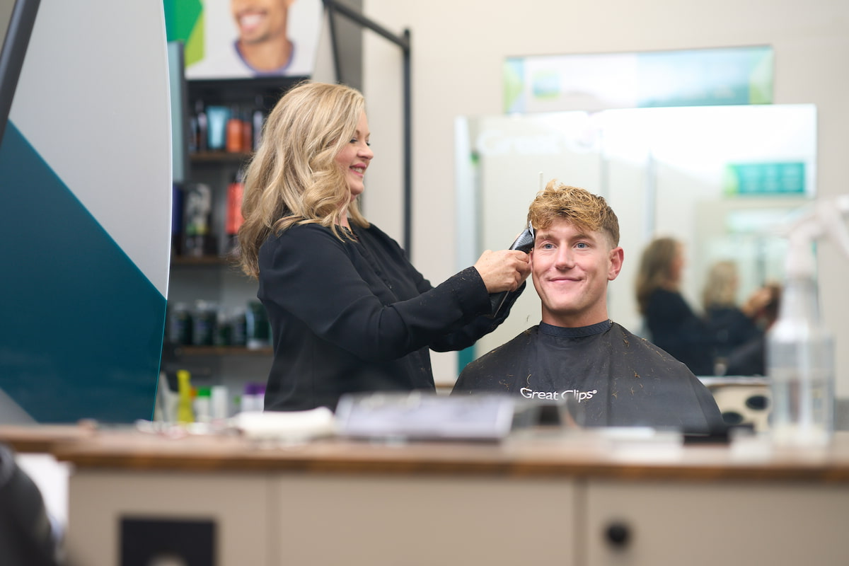 A man sitting in a Great Clips salon chair getting a haircut